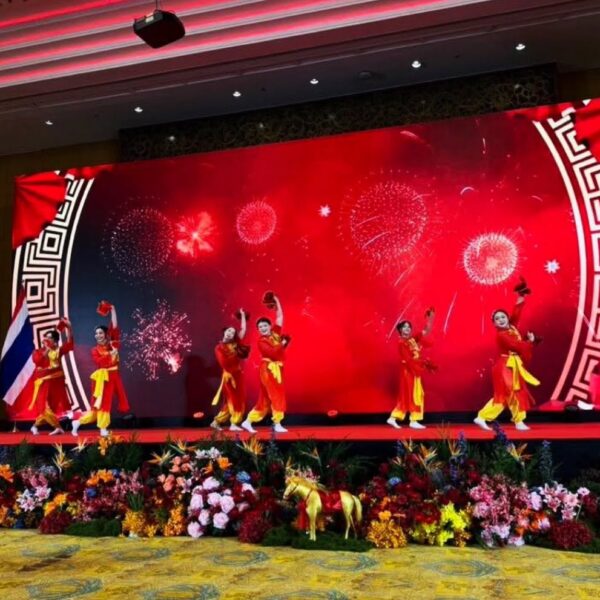 การแสดงรำพัดแบบประเพณีจีนโบราณโดยนักแสดงในชุดสีแดงและเหลืองบนเวทีงานตรุษจีน
